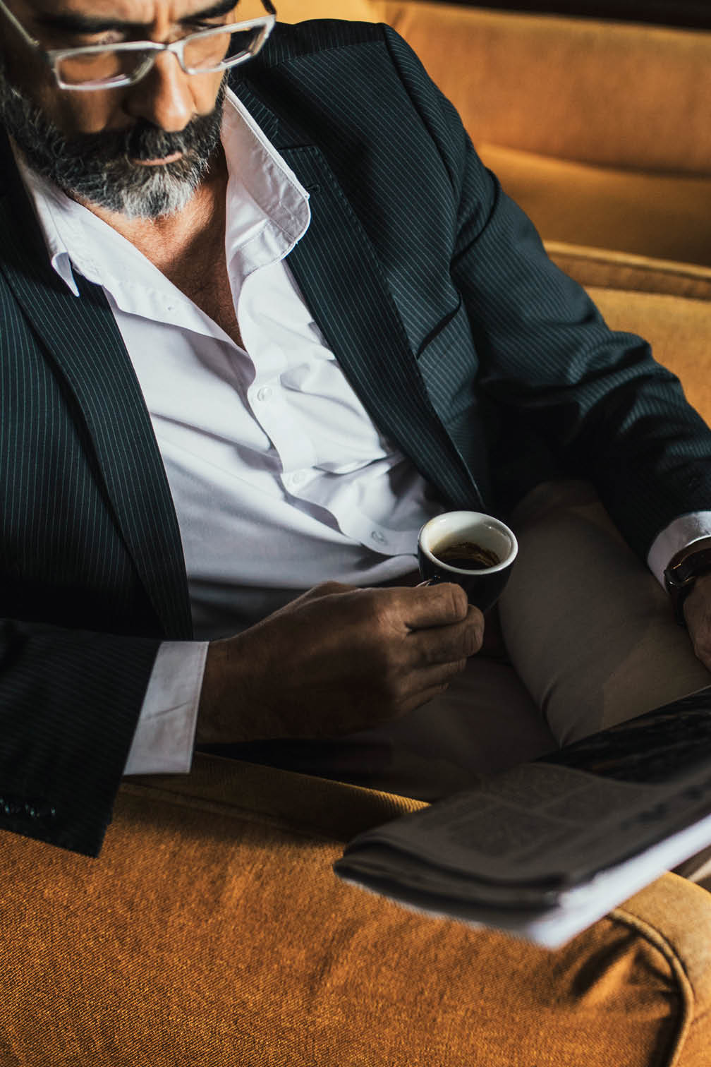Elegant Caucasian businessman drinking coffee and reading newspaper 