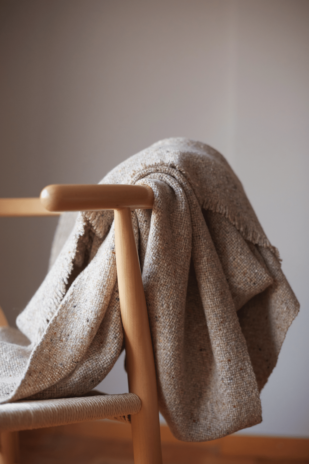 Wooden chair with a wool blanket and light grey background wall