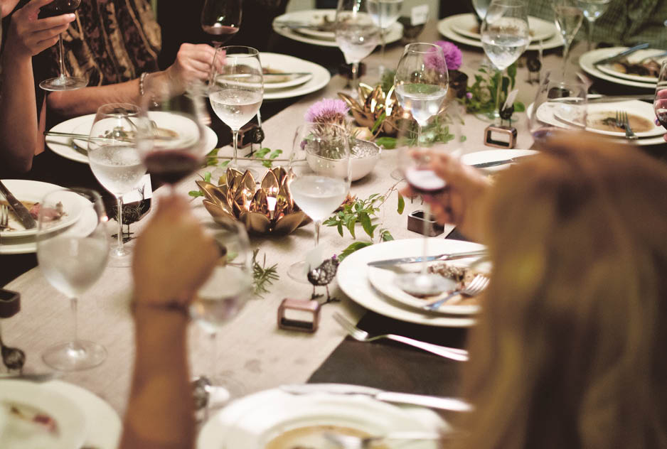 Several plates of food in front of guests at a dinner party 